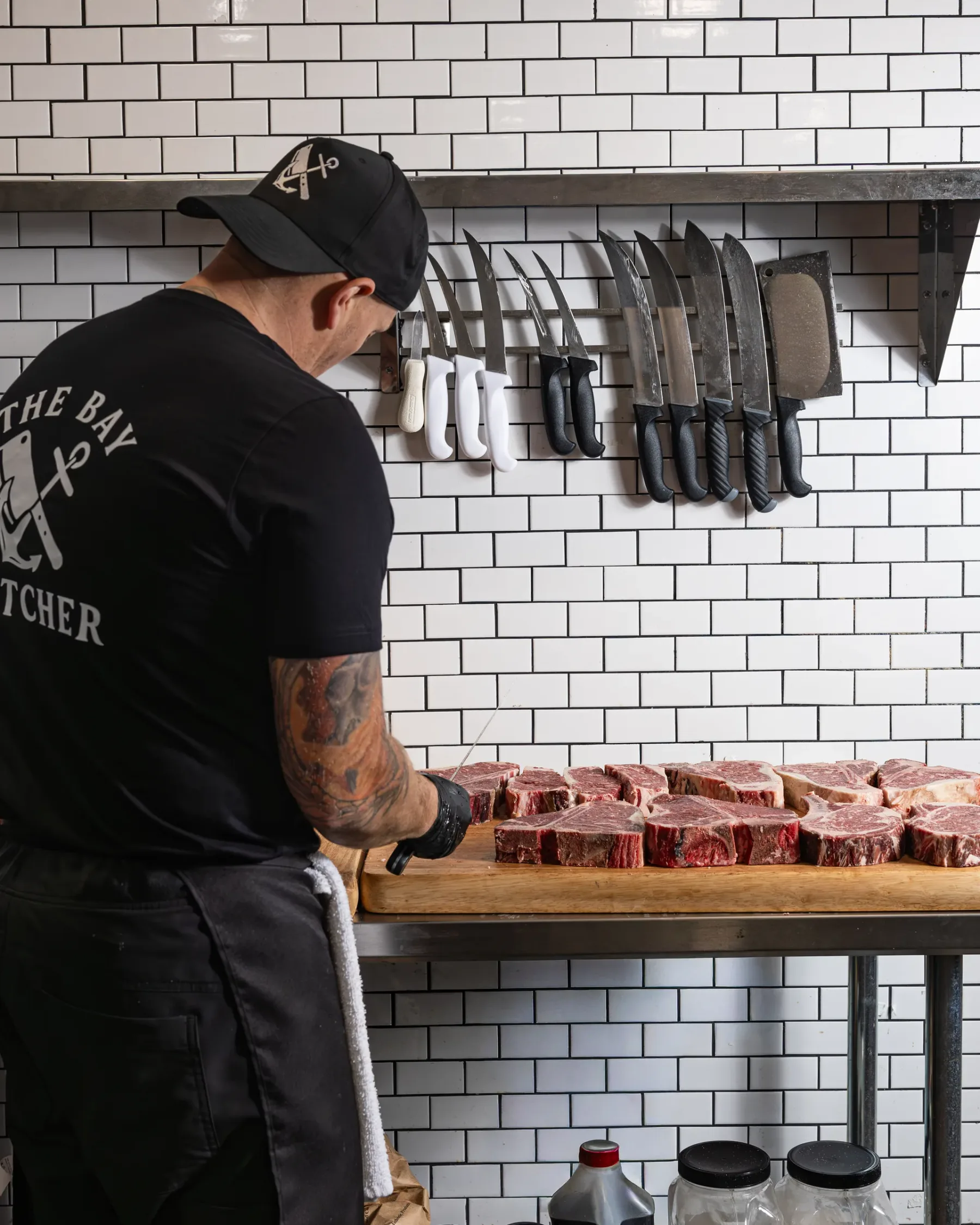 A butcher at work behind the counter at The Bay Butcher