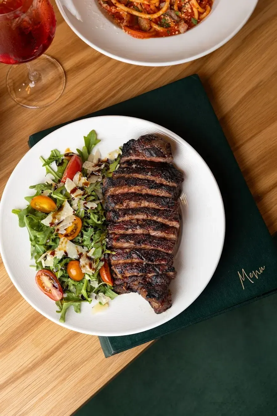 A sliced steak served over greens