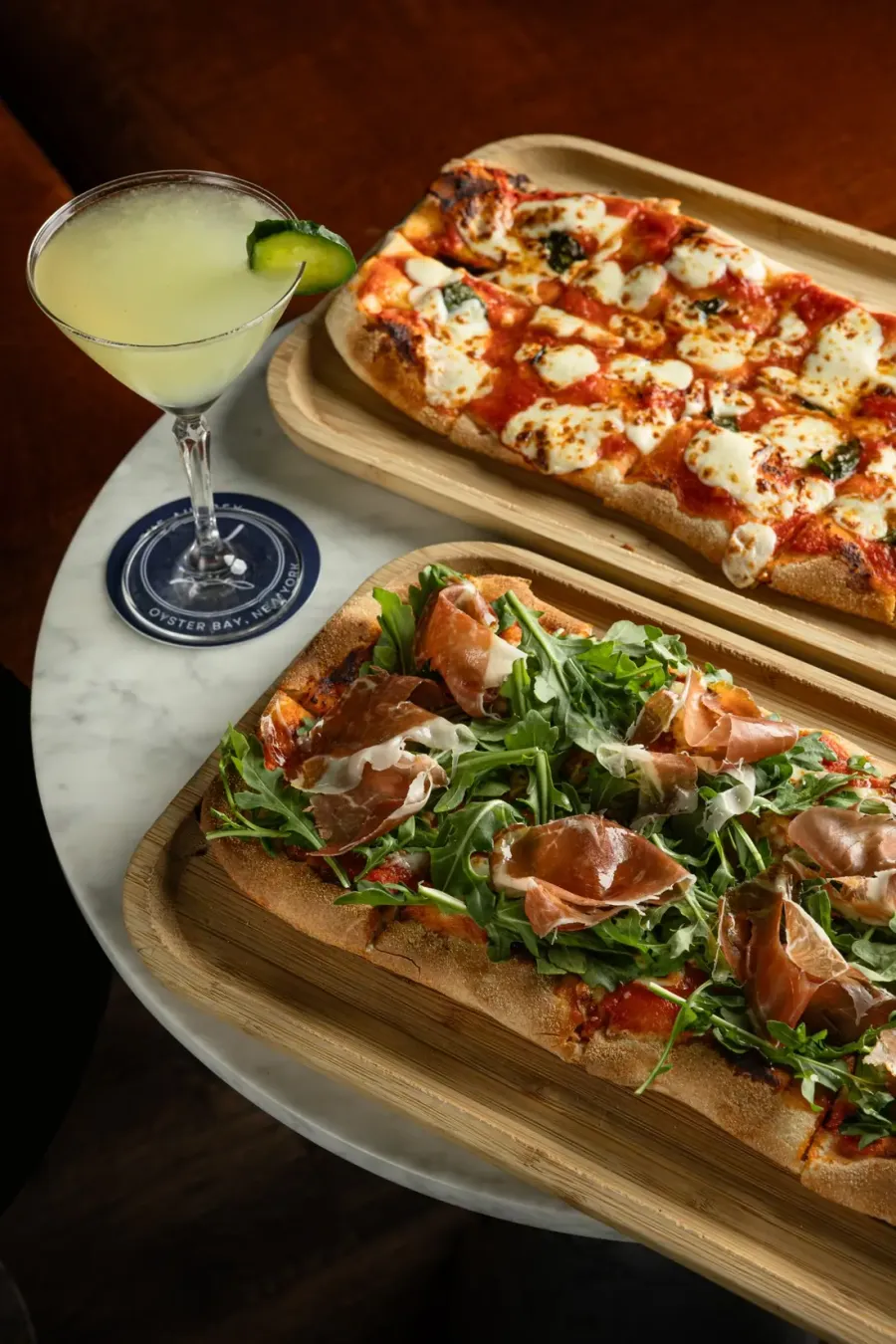 Two flatbreads on boards with a cocktail
