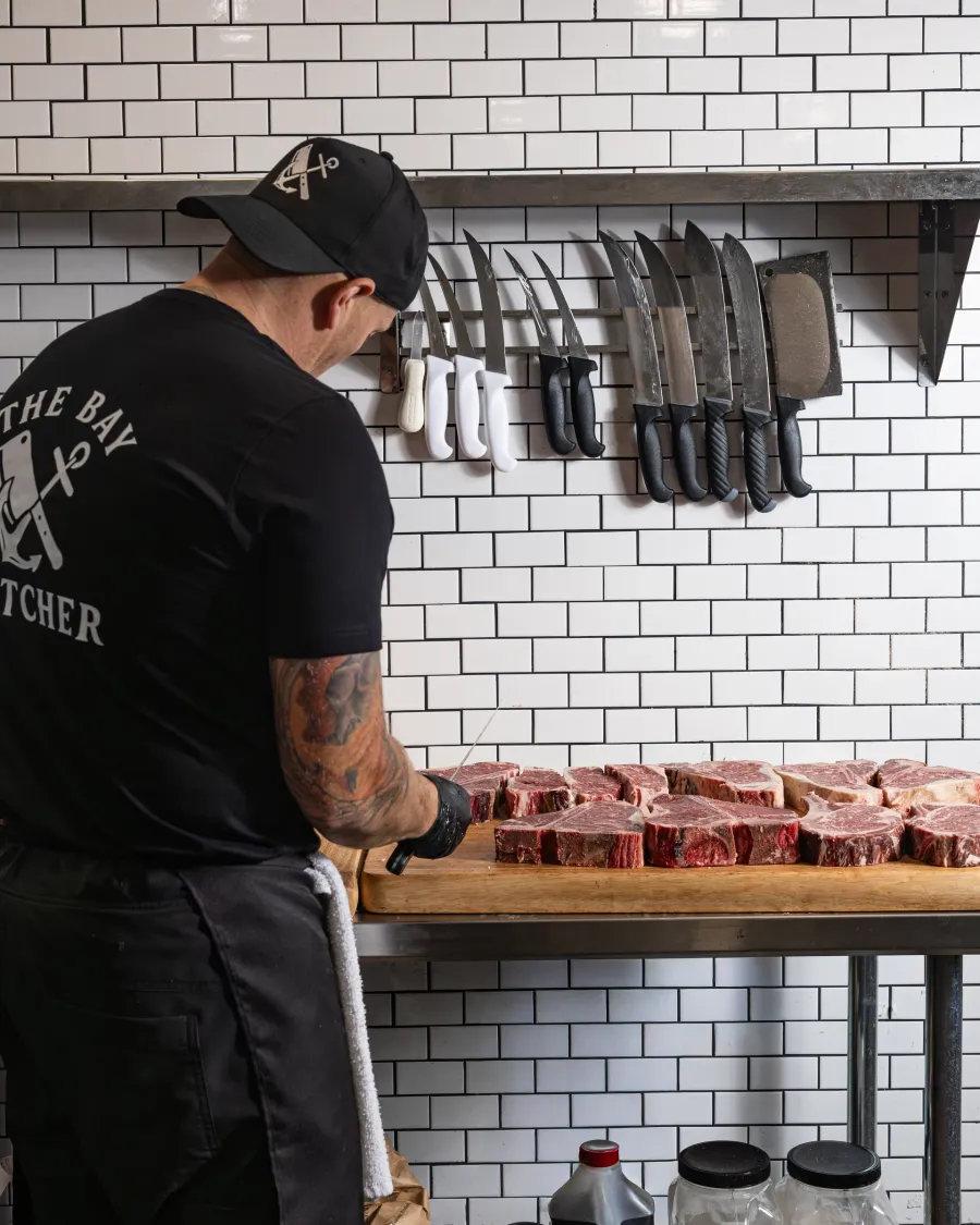 A butcher working the counter beneath a wall of knives